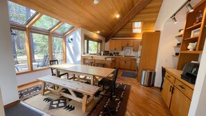 A spacious kitchen with wooden cabinets, a dining area with a large table and chairs, and large windows providing natural light. - GM239: Private Hot Tub + Family/Dog Friendly + Central AC (Sisters)