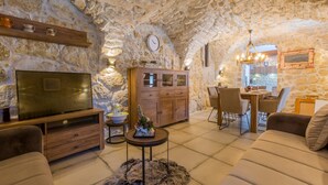 Un salon chaleureux avec des murs en pierre, un meuble en bois, un téléviseur et des sièges confortables.