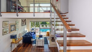 A spacious living area with a high ceiling, a wooden staircase, a pool view, and a modern sofa set. - Villa Hana (Dramalj)