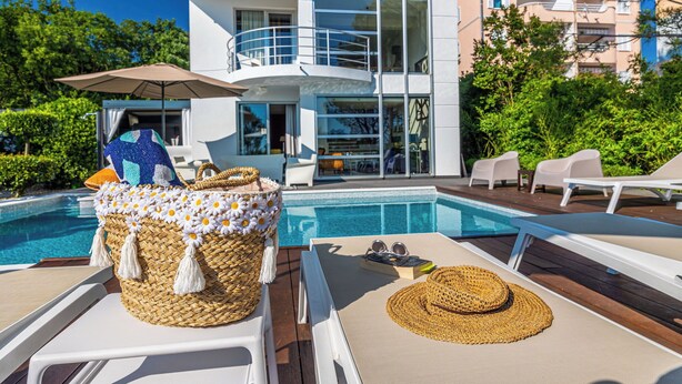 A modern house with a pool, white lounge chairs, and a wicker basket with a hat. - Villa Hana (Dramalj)