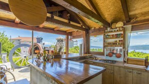 Une cuisine rustique avec un îlot central en pierre, des armoires en bois et une vue sur l’extérieur.