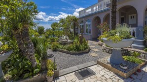 Une cour avec une fontaine, des plantes en pot et un bâtiment doté d’arcades et d’un balcon.