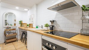 Une cuisine moderne avec des carreaux blancs, un plan de travail en bois, une cuisinière et une fenêtre donnant sur un beau paysage.