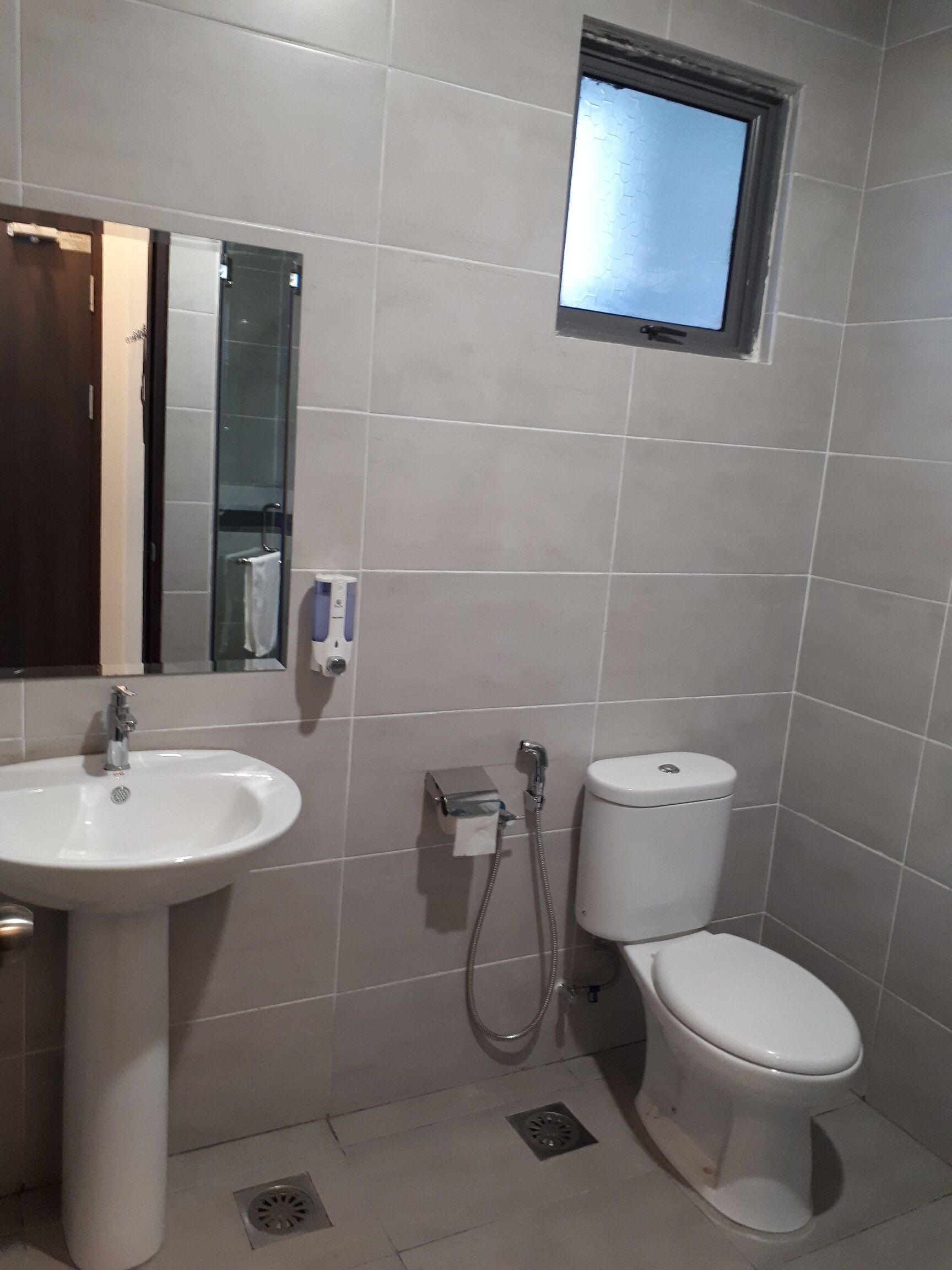 A bathroom with a sink, toilet, and a small window.