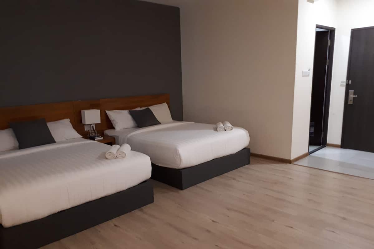A hotel room with two beds, a wooden headboard, a nightstand, and a door.
