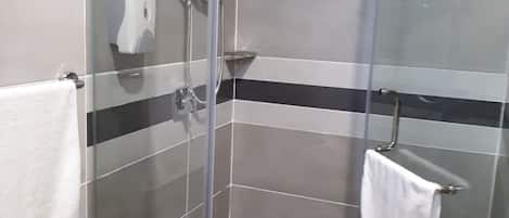 Ducha envuelta en vidrio con cabezal de ducha de mano y grifo empotrado.