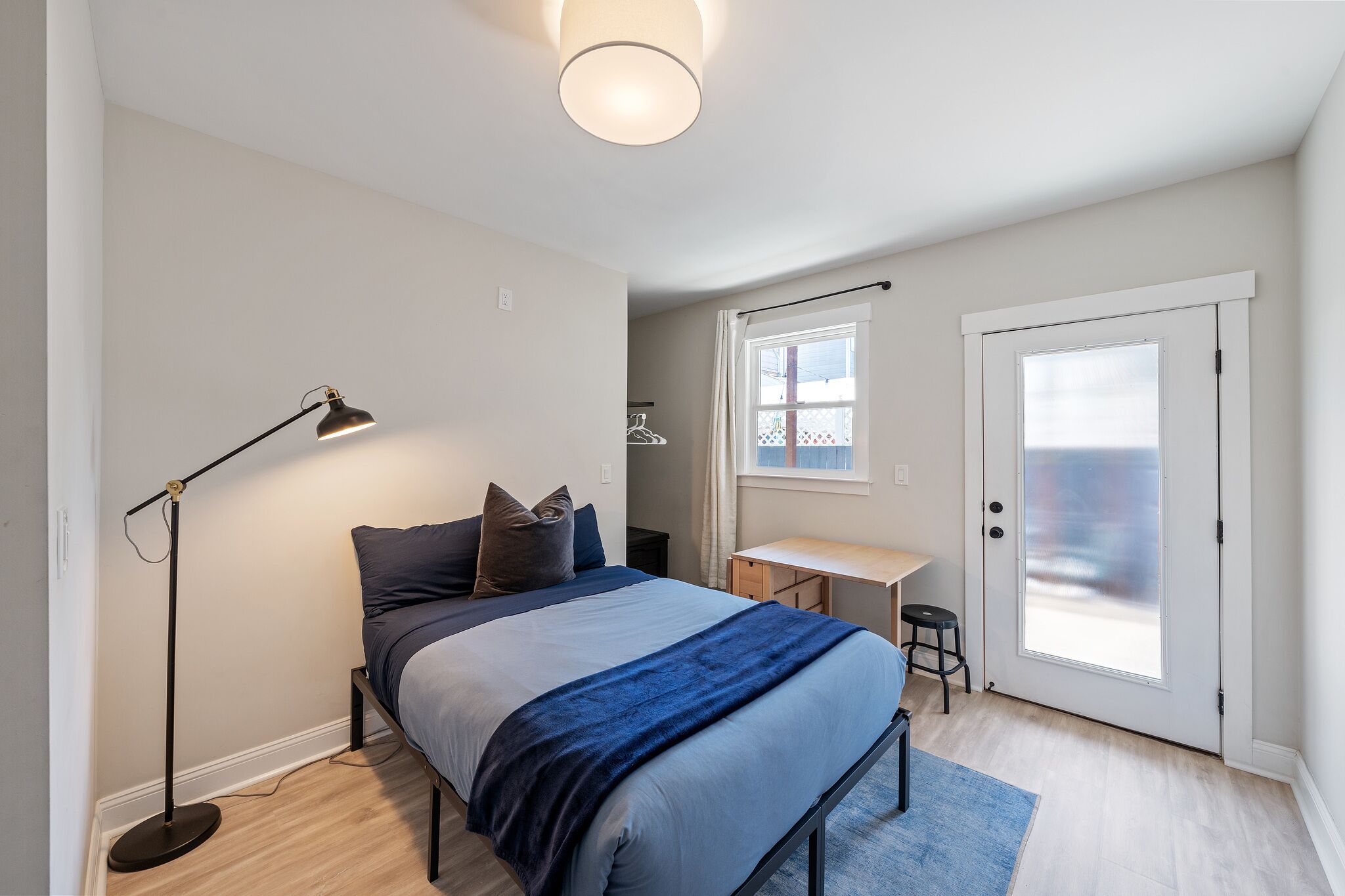 Une chambre à coucher comprenant un lit, une table de chevet, un bureau et un lampadaire.