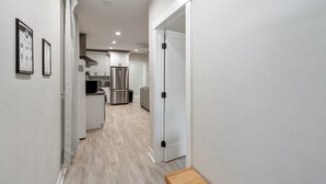 A modern kitchen with stainless steel appliances, a wooden floor, and white cabinetry.