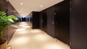 Un pasillo moderno con suelo de madera, taquillas oscuras e iluminación empotrada en el techo.
