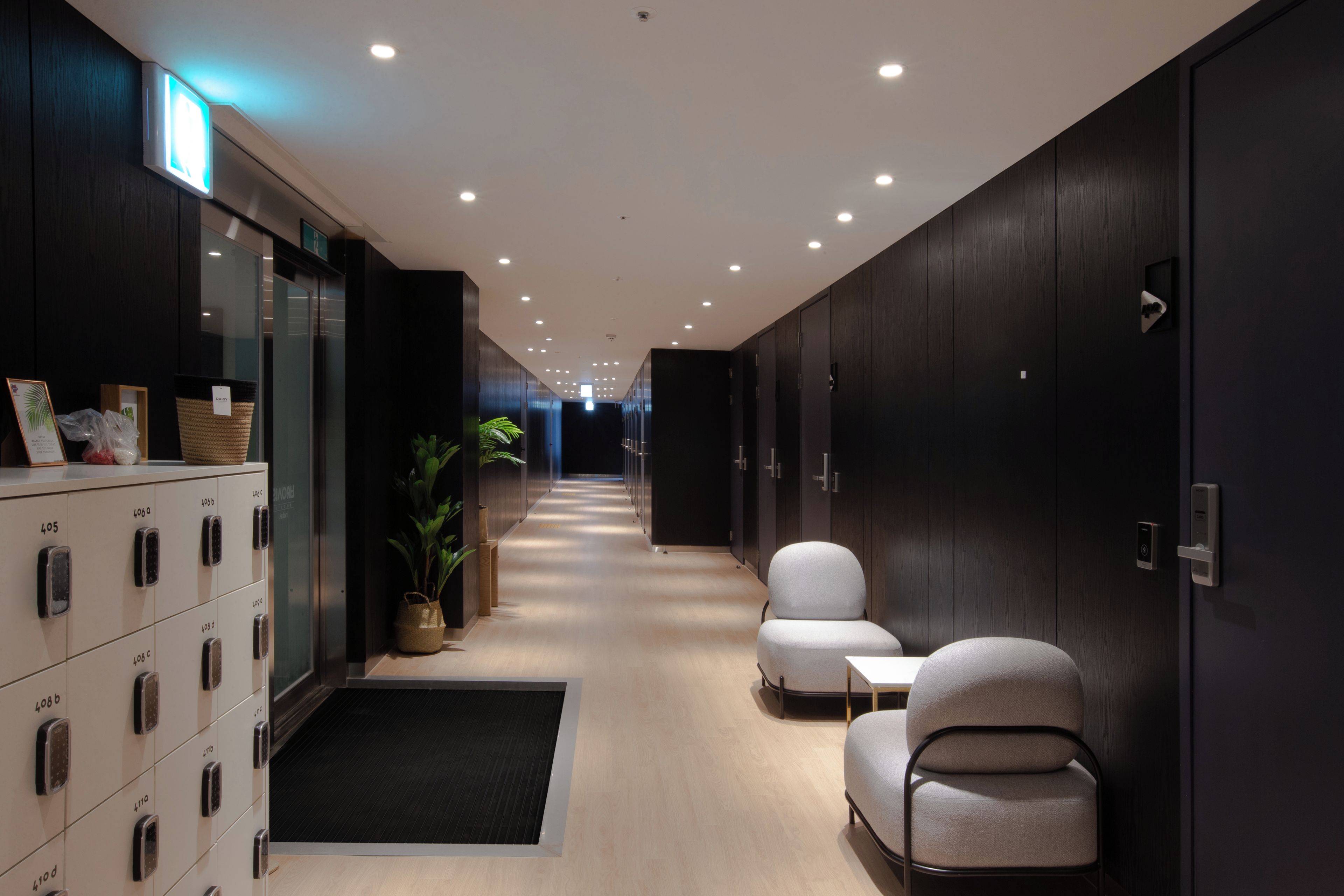 Un hall de hotel con mostrador de recepción, taquillas, zona de estar y un largo pasillo que conduce a otras habitaciones.
