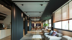 Un moderno vestíbulo de hotel con mostrador de recepción, zona de estar y grandes ventanales.