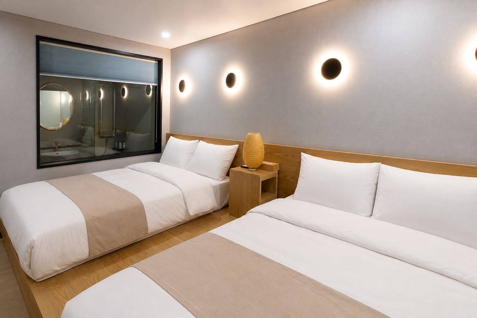 A hotel room with two beds, a large mirror, and wall-mounted lighting.
