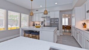 A modern kitchen with white cabinets, a central island, and pendant lighting.