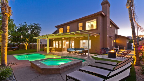A two-story house with a covered patio, a swimming pool, and outdoor seating.