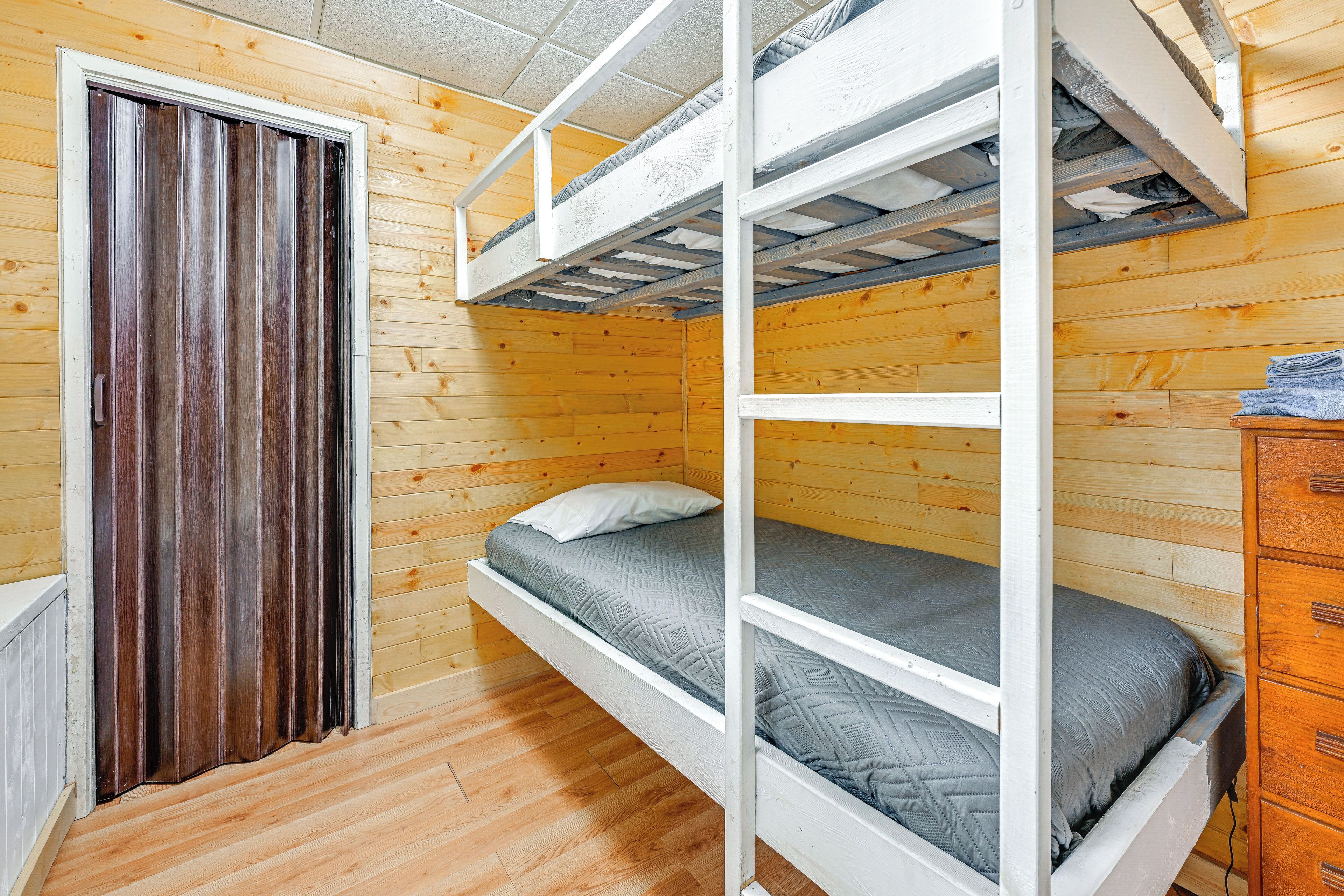 A bunk bed room with wooden walls and a door.
