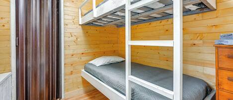 A bunk bed room with wooden walls and a door.
