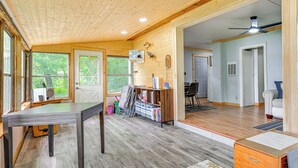 A spacious room with a wooden ceiling, a large window, and a door leading to another room. - Lakefront Cabin w/ Fire Pit, Dock, & Boat Rental (Augusta)