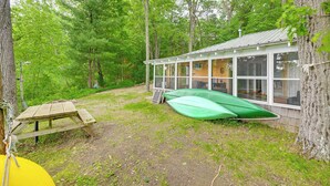A cabin with a glass enclosure, a picnic table, and a green canoe. - Lakefront Cabin w/ Fire Pit, Dock, & Boat Rental (Augusta)