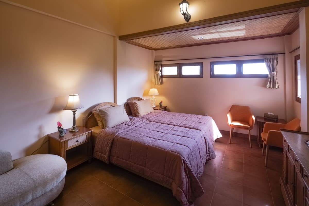 A bedroom with two beds, a nightstand, a chair, and a desk.