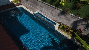 A rectangular swimming pool with clear blue water, surrounded by a concrete wall and a tiled deck. - Kemangi Apartments and Yoga Space (Ubud)