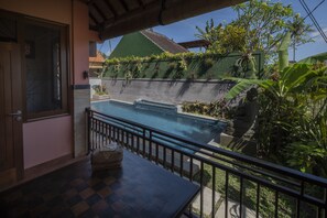 Área de piscina com vista para uma casa, uma mesa com um cesto e um corrimão.