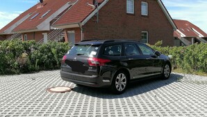 En svart Citroën DS stod parkerad framför ett hus med röda tegelväggar, ett sluttande tak och en trappa som ledde upp till en dörr med skylten "Espace".