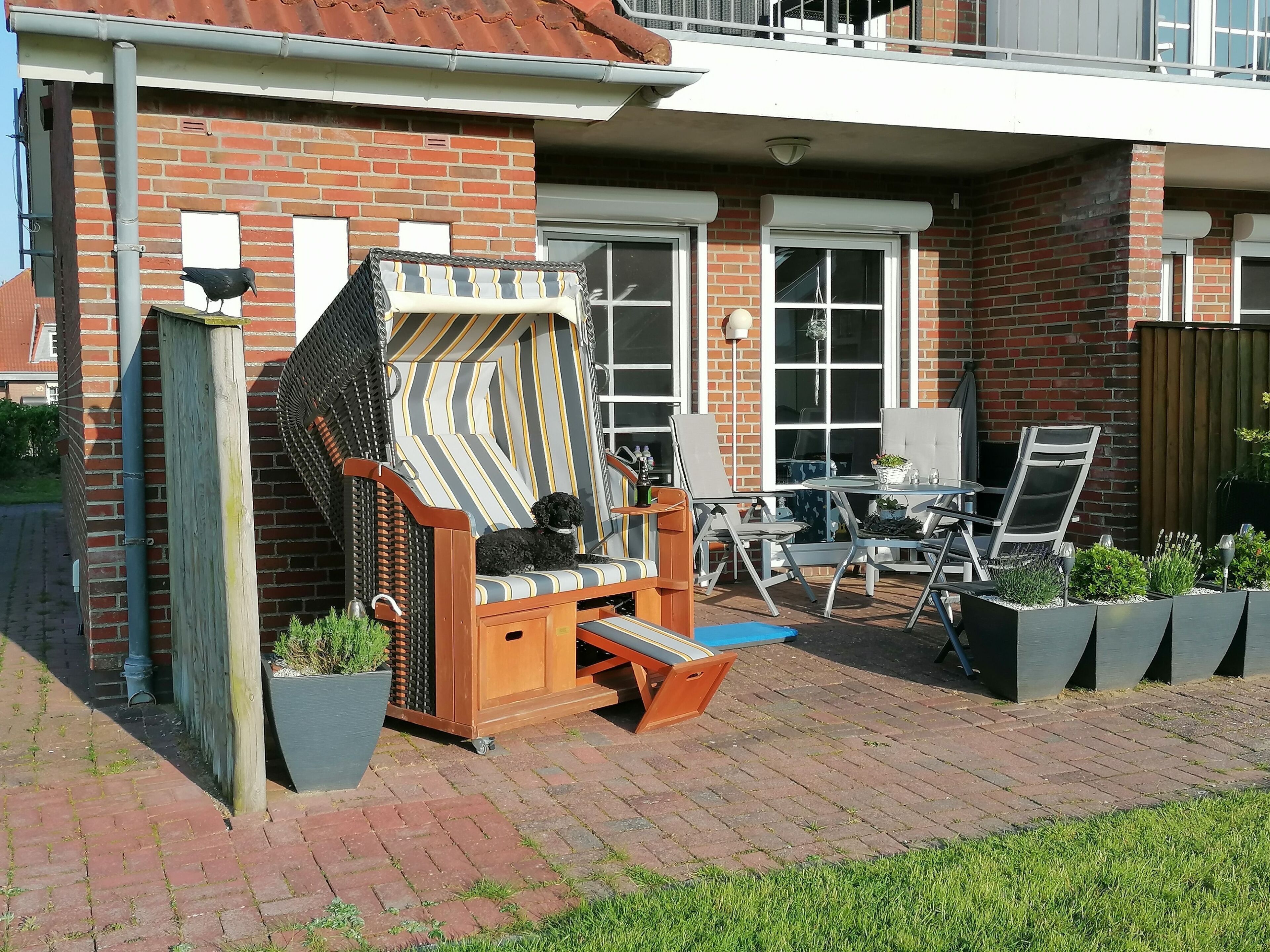 Eine Terrasse mit einem Holzstuhl, einem kleinen Tisch und einem Blumentopf.