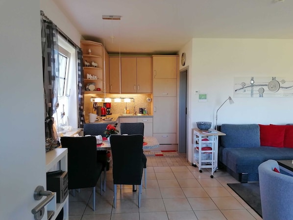 A compact living space with a dining area, kitchenette, and a sofa.