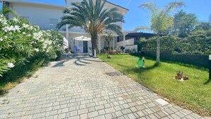 Un camino pavimentado que lleva a un edificio moderno con una zona de estar al aire libre cubierta.