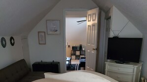 Un dormitorio con una cama grande, un aparador, un televisor y un ventilador de techo.