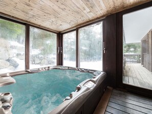 A hot tub with a wooden ceiling and large windows.