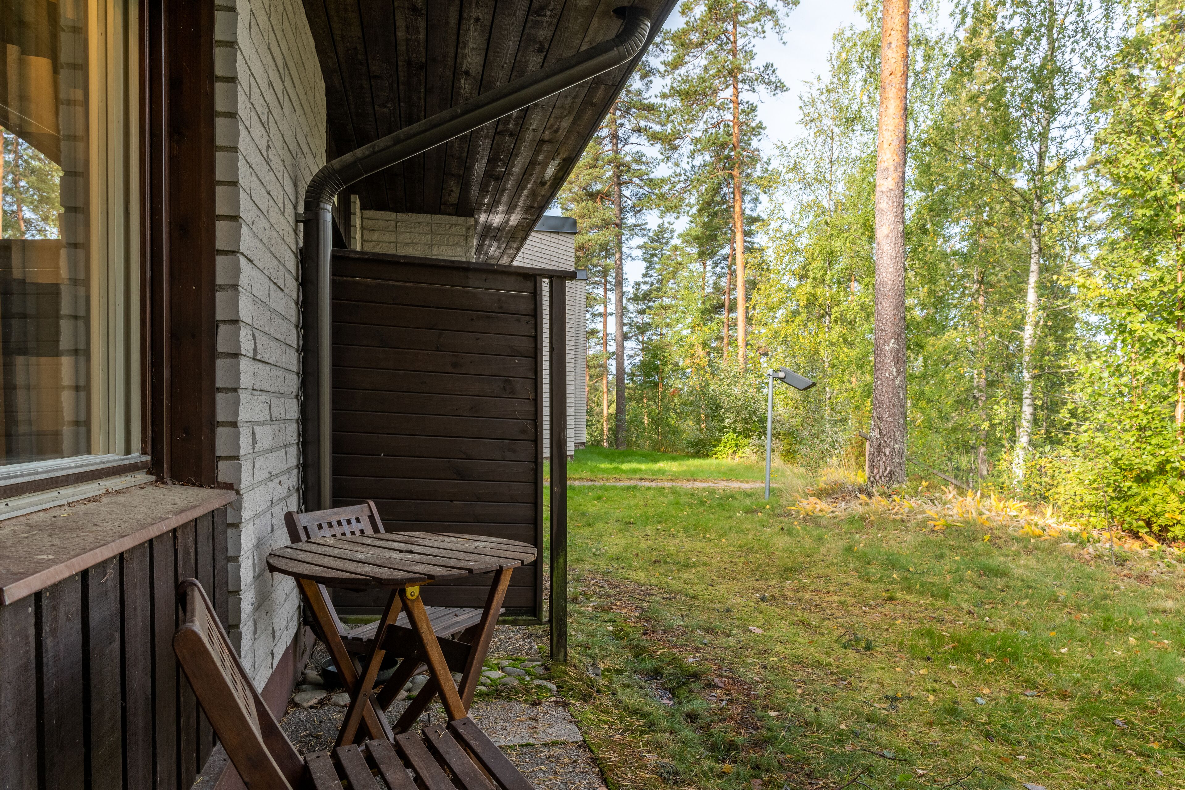 A wooden cabin with a porch, a table, and chairs.