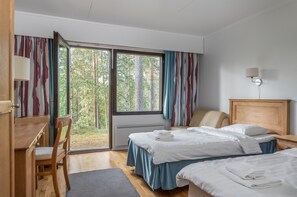 Une chambre d’hôtel avec deux lits, un bureau, une chaise et une grande fenêtre avec des rideaux.