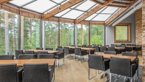 A conference room with tables and chairs, large windows, and a wooden ceiling structure.
