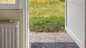 A wooden door leading to a grassy area with trees in the background.