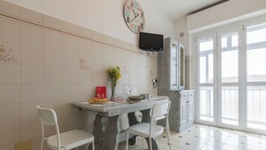 A dining area with a table, chairs, a clock, and a TV. - Apartment with a View in the Lingotto Area by Wonderful Italy (Turin)