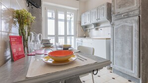 A modern kitchen with white cabinets, a marble countertop, and a dining area with a table set for two. - Apartment with a View in the Lingotto Area by Wonderful Italy (Turin)