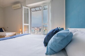 Et hotelværelse med en seng, et natbord med lampe og en balkon med udsigt til bygninger.