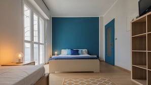 A bedroom with a bed, a bedside table with a lamp, a large window, and a wardrobe. - Apartment with a View in the Lingotto Area by Wonderful Italy (Turin)