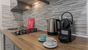 Una cocina moderna con un hervidor de acero inoxidable, una cafetera y un cartel informativo rojo en la pared.