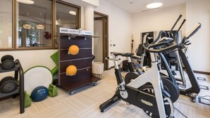 Et fitnessrum med løbebånd, vægttræningsmaskiner og en reol med træningsbolde.