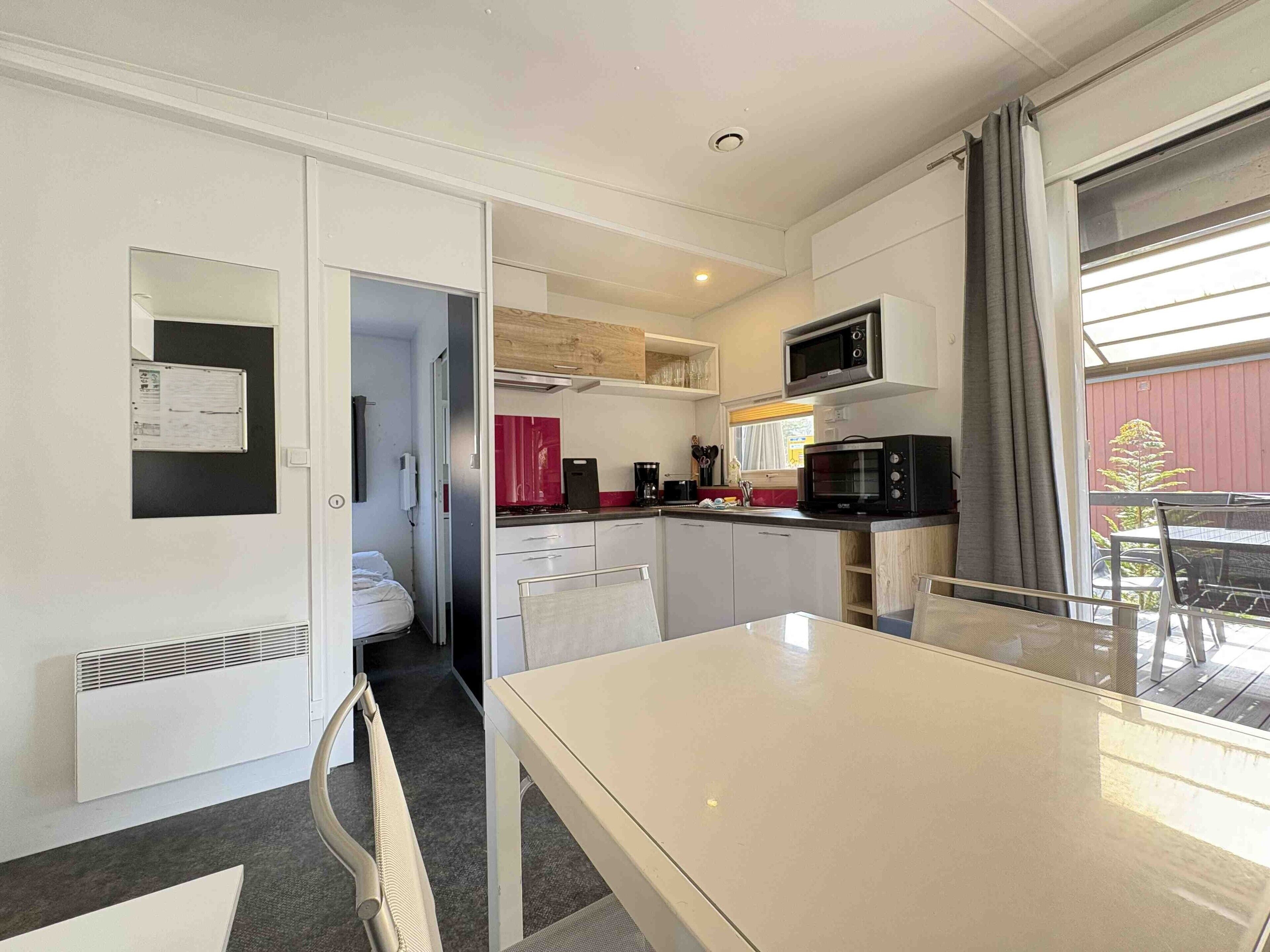 Una cocina compacta con armarios blancos, un microondas y un pequeño comedor con una mesa y sillas.