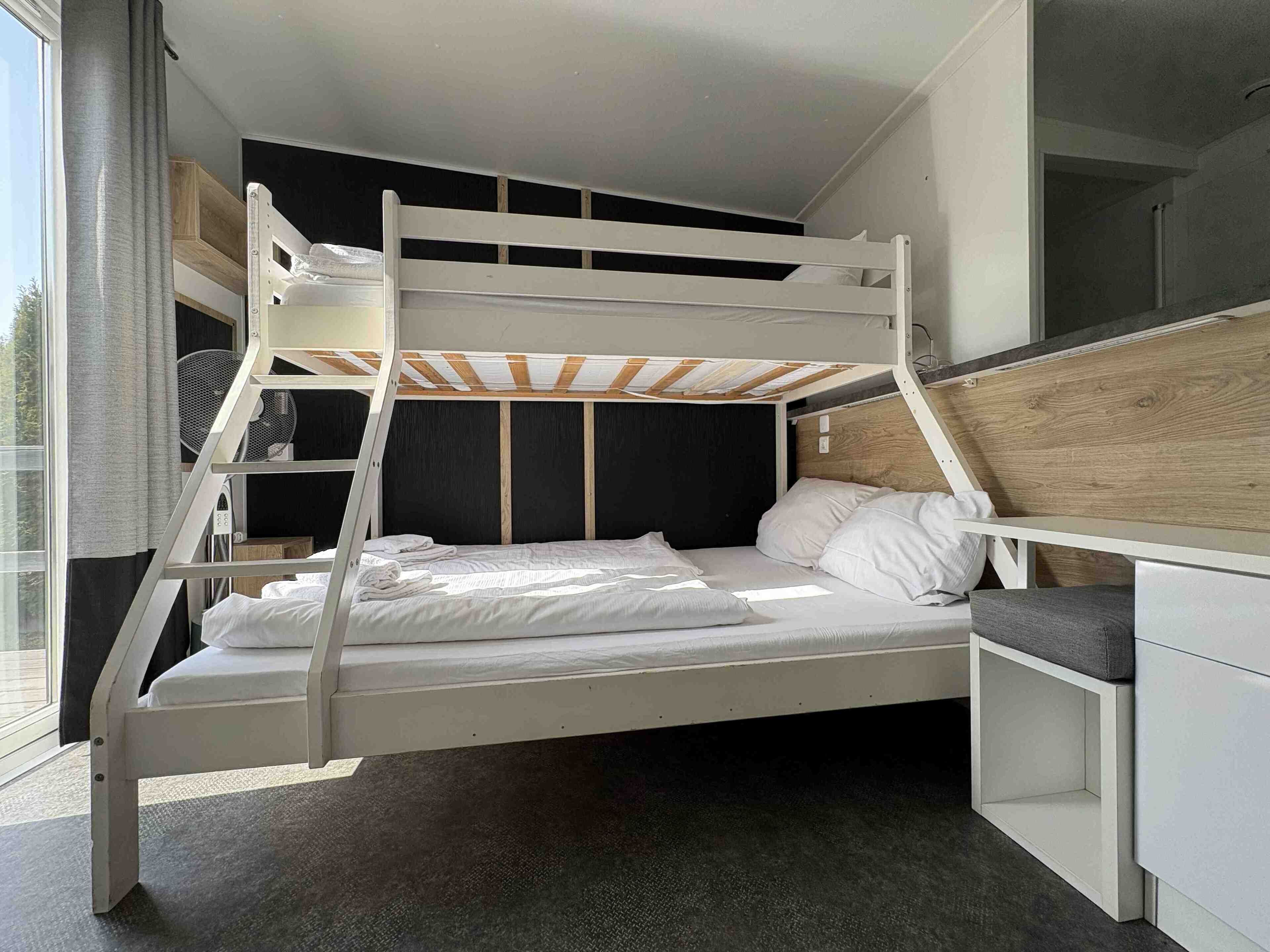 A bunk bed with a wooden headboard and a desk with a chair.