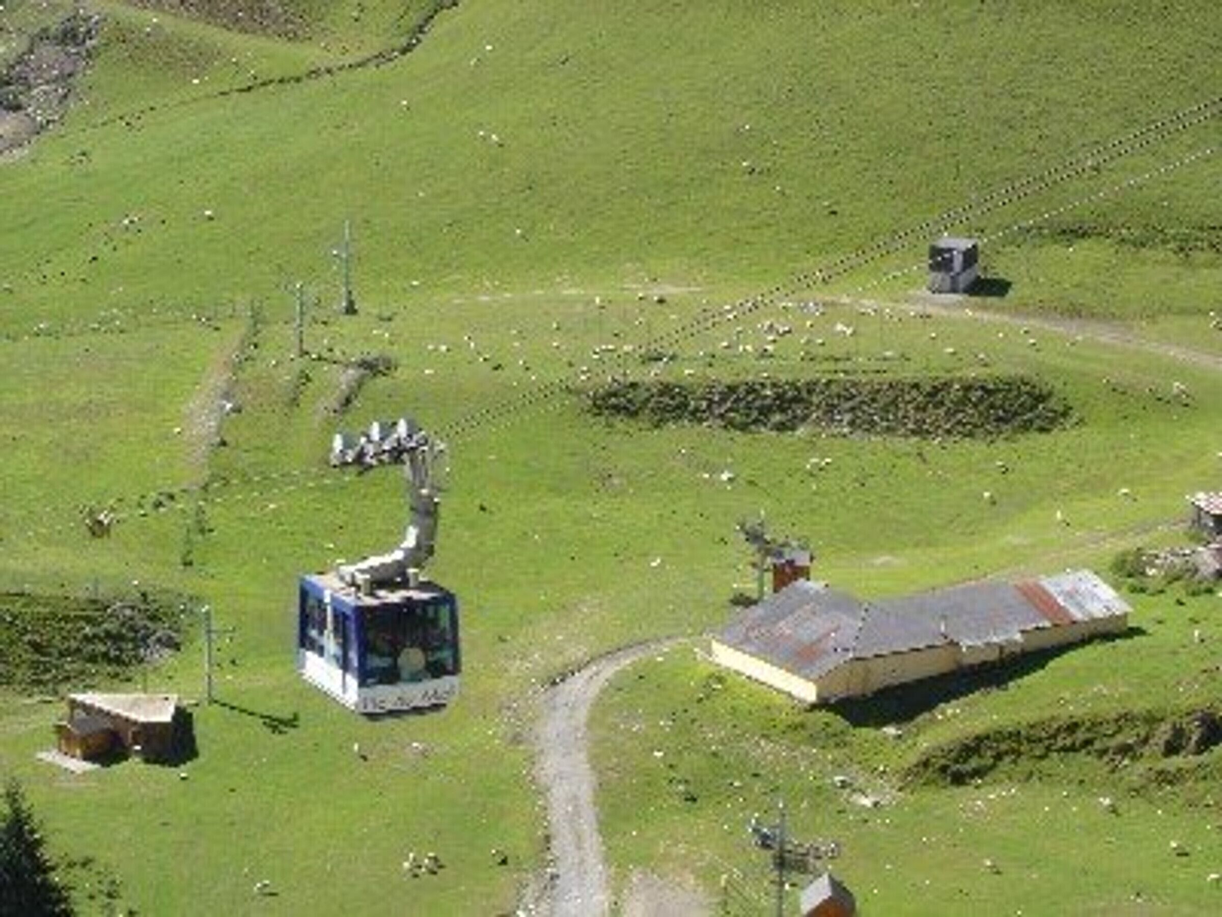 Paisaje rural con un edificio pequeño, una carretera y una gran estructura mecánica.