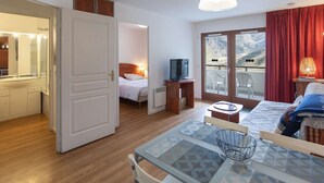 A hotel room with a balcony, a TV, a dining area, and a bathroom with a mirror. - Apartment with mountain view - 4 guests (La Mongie)