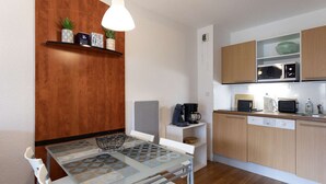 A compact kitchen with a dining table, chairs, a coffee maker, a microwave, and a dishwasher. - Apartment with mountain view - 4 guests (La Mongie)