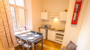 Een kleine keuken met een eettafel voor vier personen, een magnetron en een kleine koelkast.