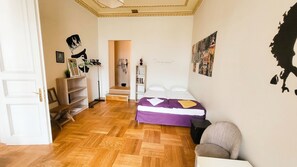 A room with a bed, a chair, a wardrobe, and a shelf with various items.
