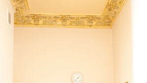 Een kleine keuken met een spoelbak, een witte deur, een klok en een spiegel aan de muur.
