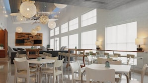 Een ruime eetruimte met modern meubilair, grote ramen en decoratieve verlichtingsarmaturen.
